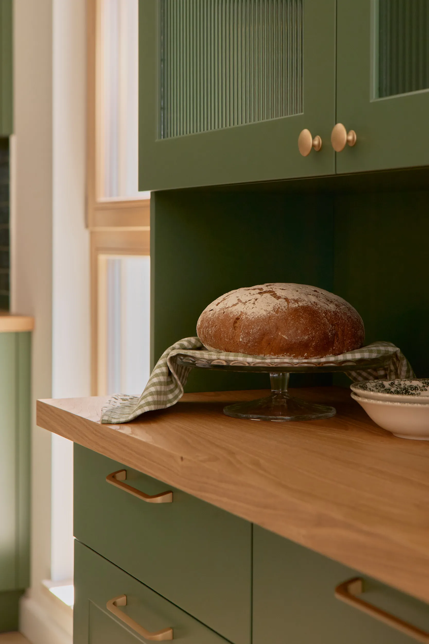 Sage green kitchen with farmhouse sink and butcher block counter